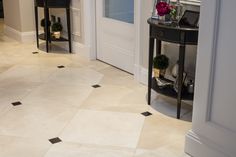 an entry way with black and white tile flooring next to a table on which is a vase filled with flowers