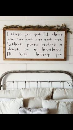 a bed with pillows and a wooden sign above it