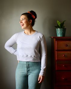 a woman standing in front of a dresser with her hands on her hips and smiling