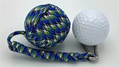 a golf ball on a metal tee with a blue, green and white striped lanyard