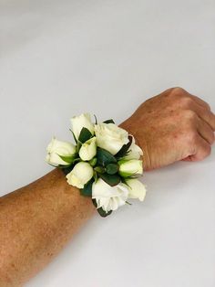 a white wrist corsage with flowers on it's left arm is shown