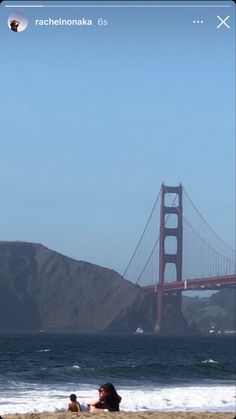 people are sitting on the beach in front of the golden gate bridge