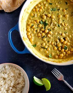 a pot filled with chickpeas and rice next to a bowl of lime wedges