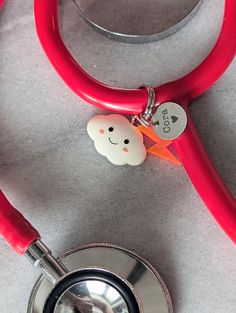 a red stethoscope with a smiley face on it next to a heart charm