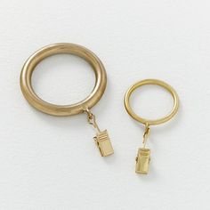 two gold rings and a keychain on a white surface, one is open