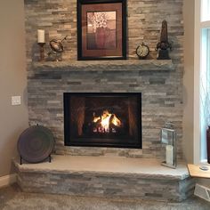 a living room with a fire place in the center and a painting on the wall above it