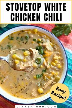 a white bowl filled with chicken and corn soup on top of a colorful table cloth