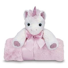 a white stuffed unicorn sitting on top of a pink blanket with a pink bow around its neck