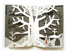 an open book with paper cut out of it's pages and trees in the background