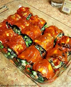 a glass casserole dish filled with meat covered in marinara sauce and vegetables