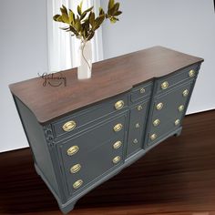 a gray dresser with gold knobs on it and a vase full of flowers sitting on top