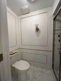 a white toilet sitting in a bathroom next to a shower