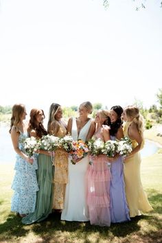 a group of women standing next to each other on top of a lush green field