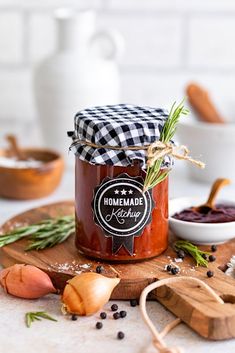 a jar of homemade ketchup sitting on top of a cutting board