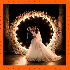 a bride and groom standing in front of a wedding arch with fairy lights on it