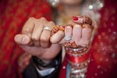 two hands holding each other with henna tattoos on their fingers and rings around them