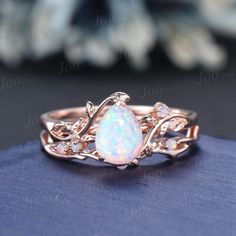 a white opal ring sitting on top of a blue cloth