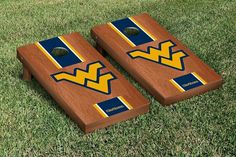 two wooden cornhole game boards with west virginia university on them sitting in the grass