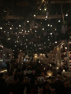 people sitting at tables in a dimly lit room with lights hanging from the ceiling above them