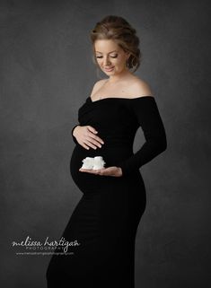 a pregnant woman in a black dress holding a piece of cake