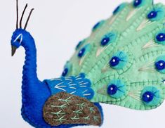 a blue and green peacock ornament hanging on a wall