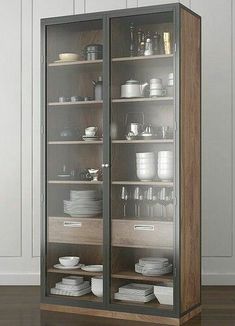 an empty glass cabinet with plates and bowls in it on the floor next to a white wall