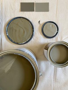 three paint cans with different shades of brown on them and one is empty, the other two are gray