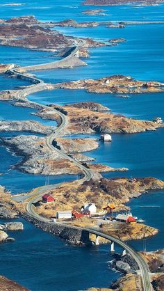 an aerial view of a winding road in the middle of water and land with houses on it