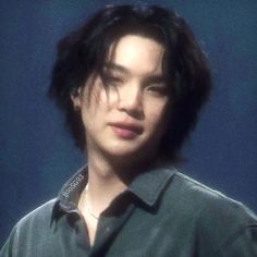 a young man with black hair wearing a green shirt