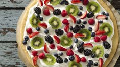 a pie topped with fresh fruit on top of a wooden table