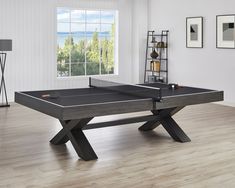 a ping pong table in the middle of a room with hardwood floors and white walls