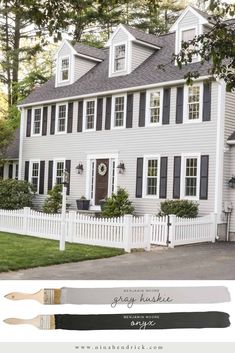 a white house with black shutters on the front, and a painting brush in front