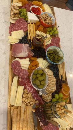 an assortment of cheeses, meats and olives on a wooden platter