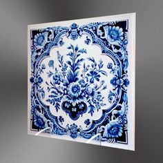 a blue and white tile with flowers on it is hanging from the wall in front of a mirror