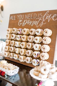 doughnuts are arranged on a wooden sign that says all you need is love and sprinkles