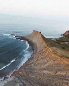 an aerial view of the ocean and beach with waves coming in from the shore line