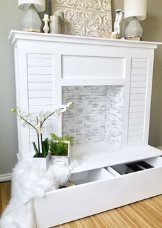 a white fireplace mantel with two drawers and a vase filled with flowers on top