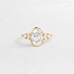 an oval shaped diamond ring with three small diamonds on the band, set in yellow gold