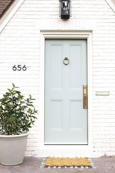 a white house with a blue door and potted plant