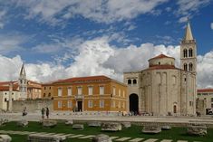 an old church and cemetery in the middle of a grassy area with people walking around