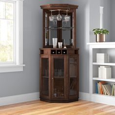 a tall wooden china cabinet with wine glasses on it's glass doors and shelves