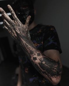 a man wearing a mask and holding his hand up to the camera with tattoos on it