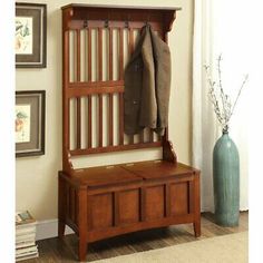 a wooden bench with coat rack and two coats hanging on it's back wall