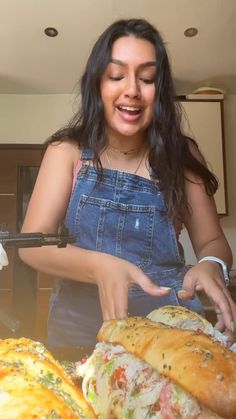 a woman in overalls cutting up a sandwich