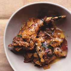 a white bowl filled with meat covered in sauce