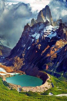 the mountains are covered in snow and green grass, with a small lake below them