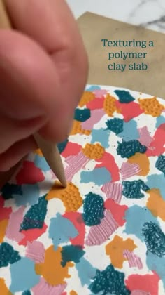 a person is using a pencil to write on a piece of paper with colorful flowers