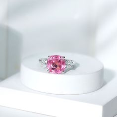 a pink diamond ring sitting on top of a white box