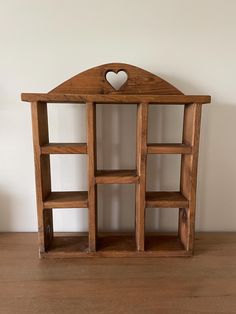 a wooden shelf with shelves and a heart on it's top, in front of a white wall