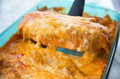 a casserole dish with cheese being lifted by a spatula